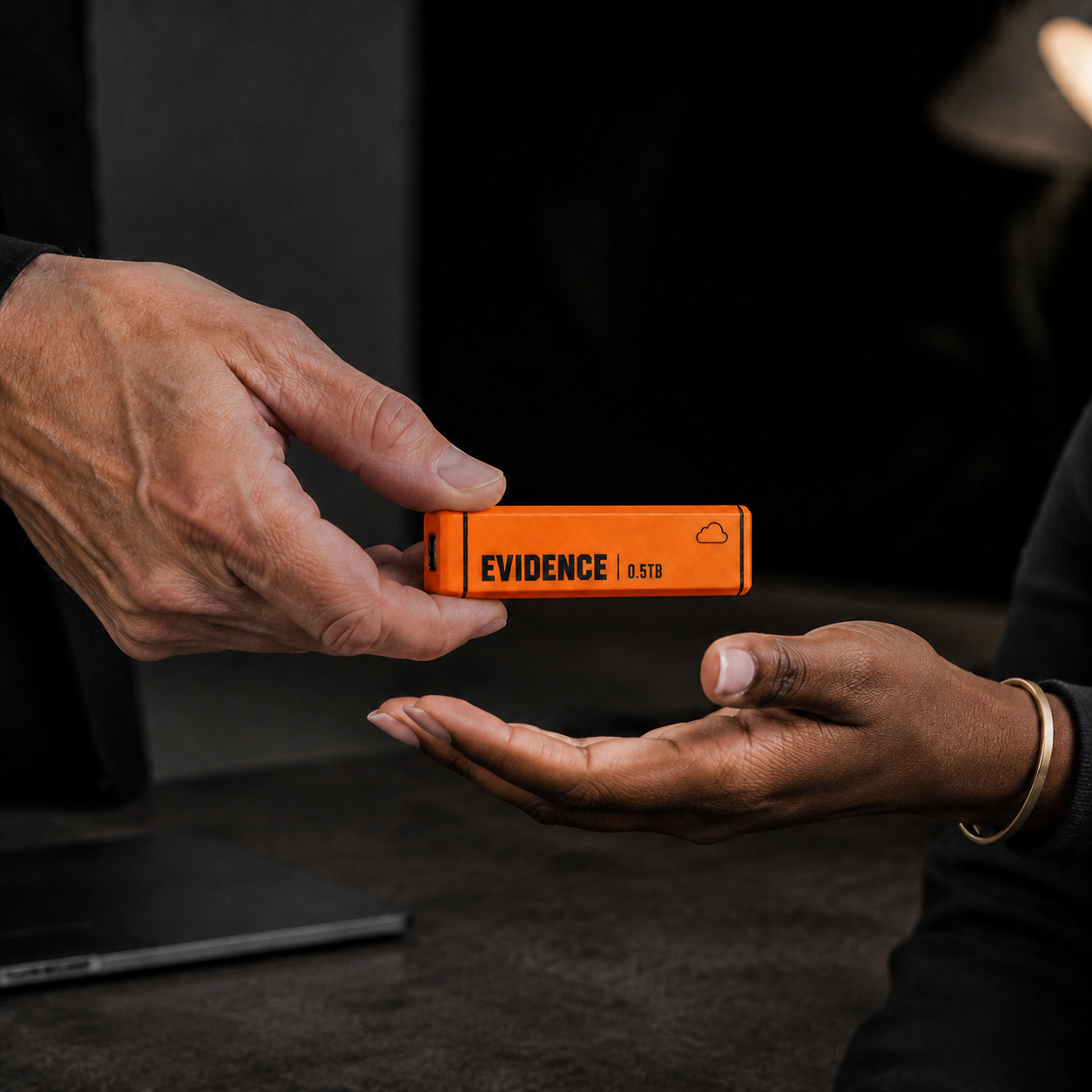 One hand passing the orange Evidence Collector to another hand